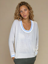 Pull manches longues col rond. Le pull est beige, a un col blanc très arrondi rehaussé d'une bande bleu ciel, détail présent aussi sur le bas des manches. Coupe souple avec une asymétrie sur les côtés.
Composition: 83%viscose et 17% nylon. Vue face.