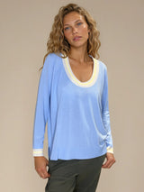 Pull manches longues col rond. Le pull est ciel, a un col beige très arrondi rehaussé d'une bande jaune, détail présent aussi sur le bas des manches. Coupe souple avec une asymétrie sur les côtés.
Composition: 83%viscose et 17% nylon. Vue face.