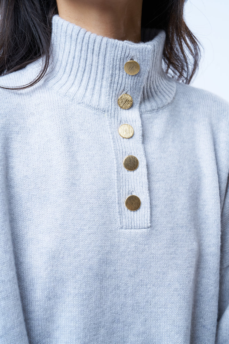 Pull camionneur gris clair pour femme. La coupe est oversize, le col est féminisé par 4 boutons dorés brossés, il peut s'ouvrir. Les emmanchures sont basses pour apporter plus d'ampleur. Il est fendu sur les côtés et asymétrique. Finitions larges côtes sur les manches et le bas. Détail du col avec les boutons dorés.
Composition: 42%cachemire, 8% soie, 50%mérinos.











