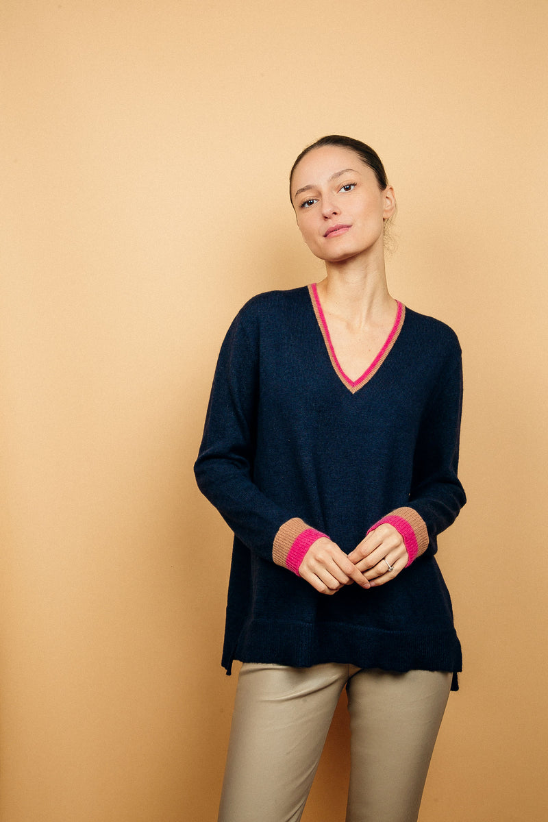 Pull EMILIA fond marine avec col V et bas de manches longues bicolores: bandes camel et fushia. Fentes côtés asymétriques. Composition: 50%mohair, 36%nylon, 14%laine.
