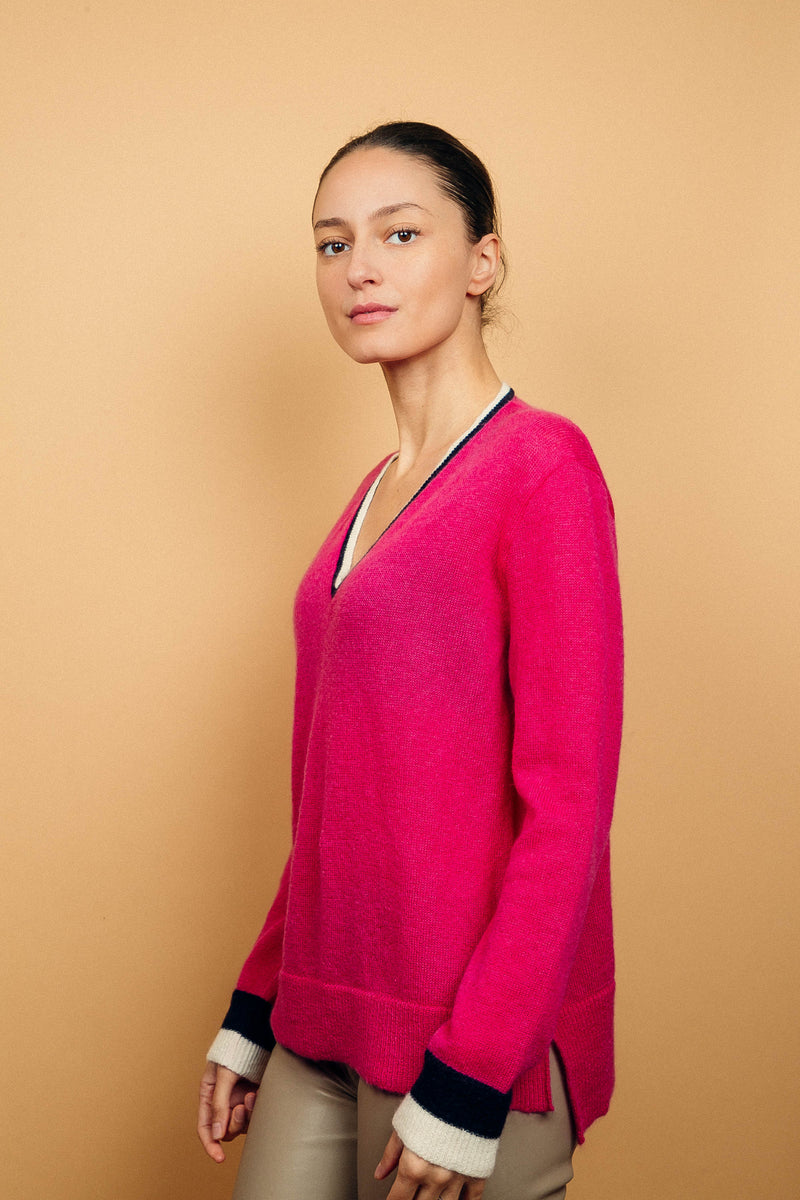 Pull EMILIA fond rose fushia avec col V et bas de manches longues bicolores: bandes marine et écru. Fentes côtés asymétriques. Composition: 50%mohair, 36%nylon, 14%laine.
