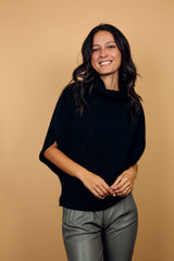 Pull col roulé sans manches noir, coupe oversize  avec une ouverture de haut en bas sur les côtés jusqu'au début des côtes de la taille. Le col est haut et souple, l'avant -bras est légèrement recouvert. Mélange de cachemire, soie et mérinos.