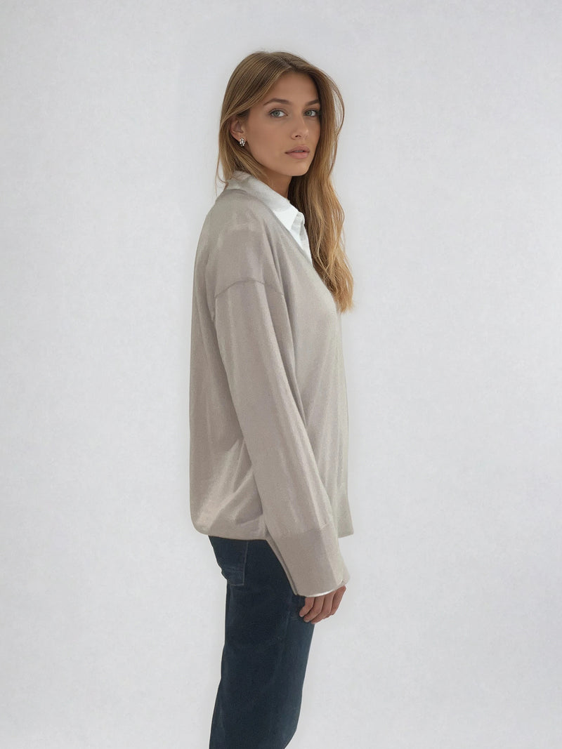 Pull manches longues col V coloris beige en 100% mérinos extra fine. L'encolure est bordée d'une bande côtelée. Les manches se terminent par de larges côtes qui permettent de porter un chemisier avec facilité. Finitions larges côtes  également sur le bas. Le pull est fendu sur les côtés sur 10 cm.
Vue profil.