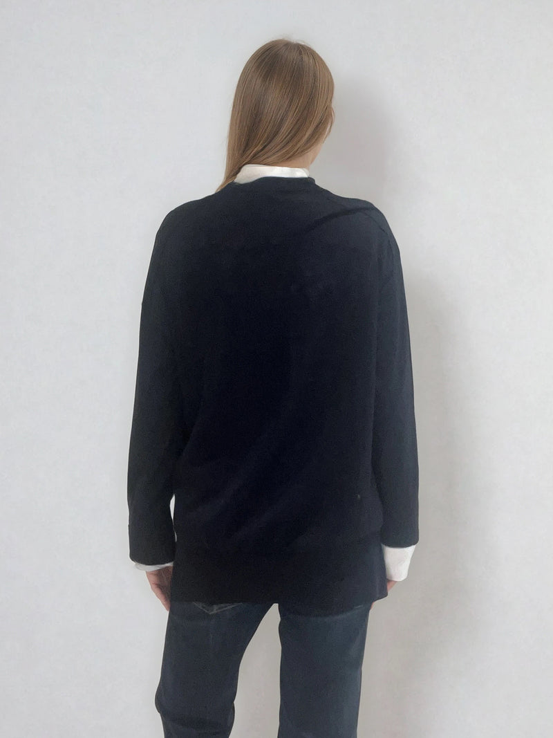 Pull manches longues col V coloris marine en 100% mérinos extra fine. Les manches se terminent par de larges côtes qui permettent de porter un chemisier avec facilité. Finitions larges côtes  également sur le bas. Le pull est fendu sur les côtés sur 10 cm. Emmanchures raglan dans le dos.
Vue dos.