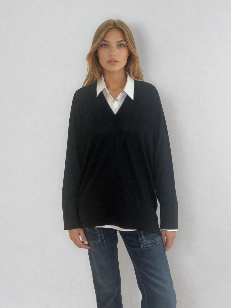 Pull manches longues col V coloris noir en 100% mérinos extra fine. L'encolure est bordée d'une bande côtelée. Les manches se terminent par de larges côtes qui permettent de porter un chemisier avec facilité. Finitions larges côtes  également sur le bas. Le pull est fendu sur les côtés sur 10 cm.
Vue face.