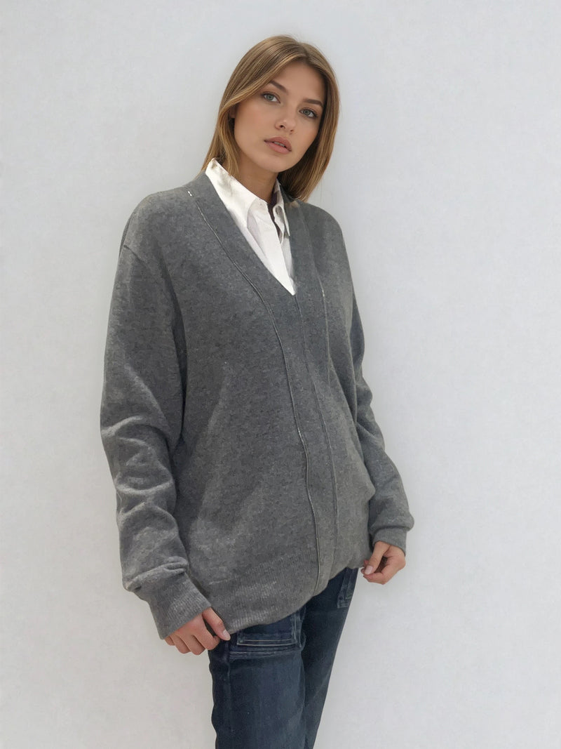 Pull manches longues coloris gris en 100% cachemire avec un col V.  Une bande de dents de fermeture éclair commence en bas et vient entourer  tout le tour de l'encolure. Coupe droite, le pull est confort et long. Finitions côtes. Vue profil.