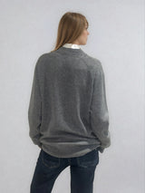 Pull manches longues coloris gris en 100% cachemire avec un col V.  Une bande de dents de fermeture éclair commence en bas et vient entourer  tout le tour de l'encolure. Coupe droite, le pull est confort et long. Finitions côtes. Vue dos.