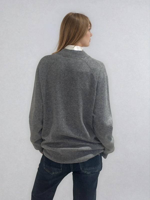 Pull manches longues coloris gris en 100% cachemire avec un col V.  Une bande de dents de fermeture éclair commence en bas et vient entourer  tout le tour de l'encolure. Coupe droite, le pull est confort et long. Finitions côtes. Vue dos.