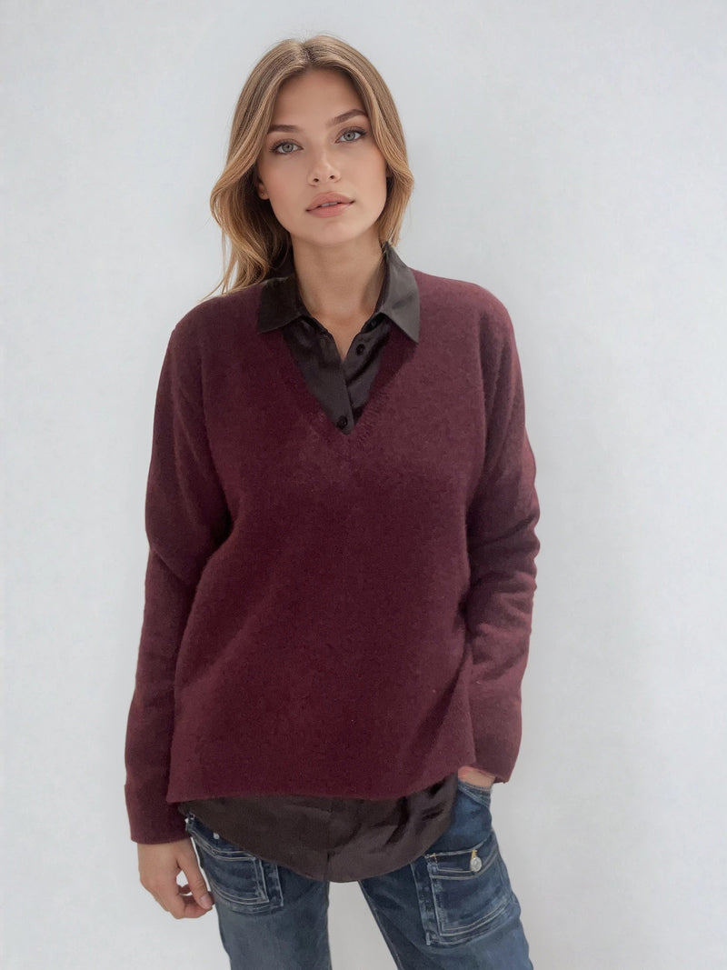 Pull manches longues coloris bordeaux avec un col V et une forme droite. Fentes asymétriques sur les côtés. Le pull est particulièrement doux, il associe du cachemire et de la soie. Finitions côtes. Vue face.