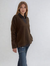 Pull manches longues coloris choco avec un col V et une forme droite. Fentes asymétriques sur les côtés. Le pull est particulièrement doux, il associe du cachemire et de la soie. Finitions côtes. Vue profil.