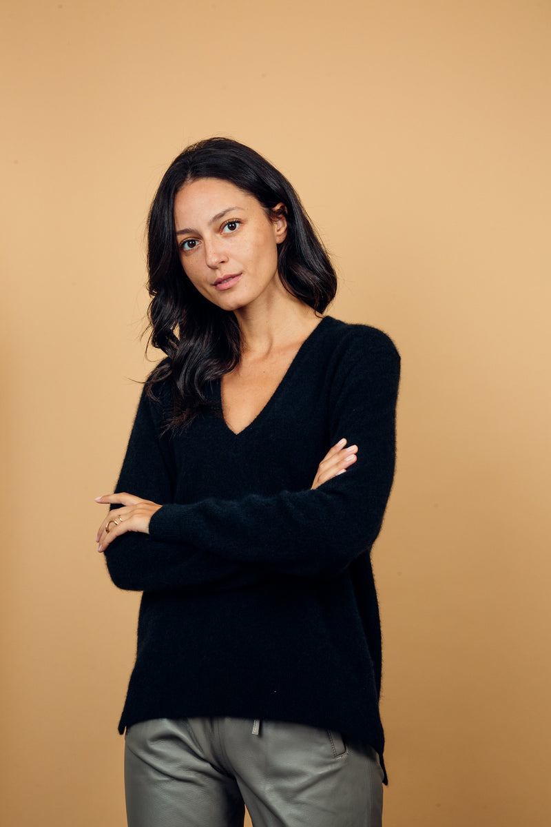 Pull manches longues coloris noir avec une forme droite. Fentes asymétriques sur les côtés. Le pull est particulièrement doux, il associe du cachemire et de la soie. Finitions côtes. Vue face.