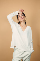 Pull manches longues coloris blanc  100% cachemire, col V profond, fendu sur les côtés avec asymétrie: 10 cm dans le dos et 7 cm devant. Finitions bords côtes. 