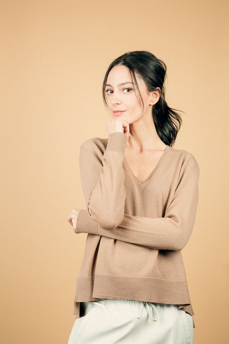 Pull manches longues coloris camel  100% cachemire, col V profond, fendu sur les côtés avec asymétrie: 10 cm dans le dos et 7 cm devant. Finitions bords côtes. 