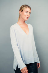 Pull manches longues coloris ciel 100% cachemire, col V profond, fendu sur les côtés avec asymétrie: 10 cm dans le dos et 7 cm devant. Finitions bords côtes. 