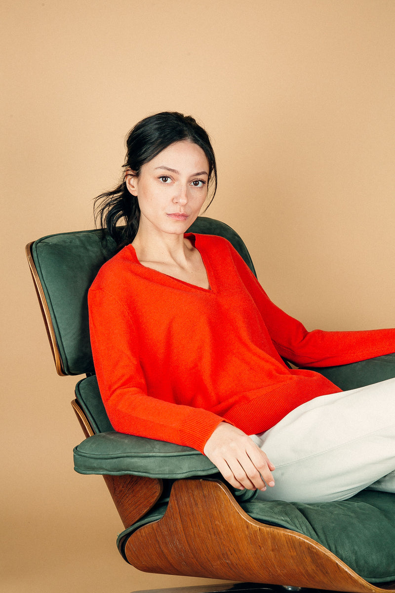 Pull manches longues coloris orange 100% cachemire, col V profond, fendu sur les côtés avec asymétrie: 10 cm dans le dos et 7 cm devant. Finitions bords côtes. 