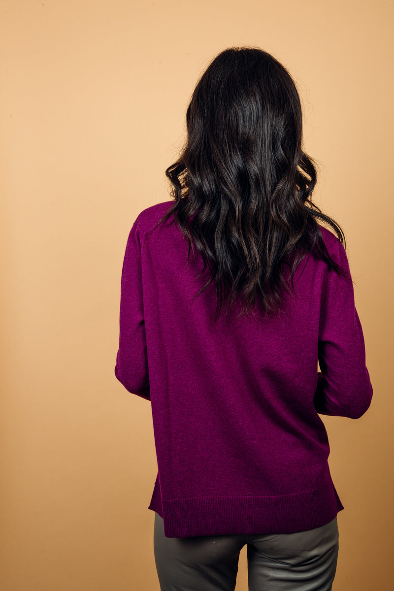 Pull manches longues coloris violet 100% cachemire, fendu sur les côtés avec asymétrie: 10 cm dans le dos et 7 cm devant. Finitions bords côtes.  Vue dos.
