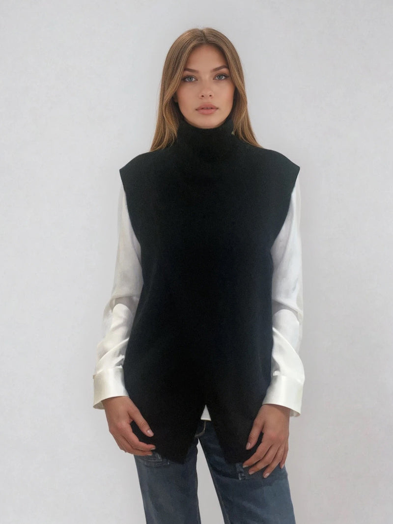 Pull sans manches noir avec un col montant et une ouverture en diagonale sur le devant formant un croisé. A porter avec un chemisier en dessous. Coupe droite et longue.  42% cachemire, 8% soie, 50% mérinos. Vue face.
