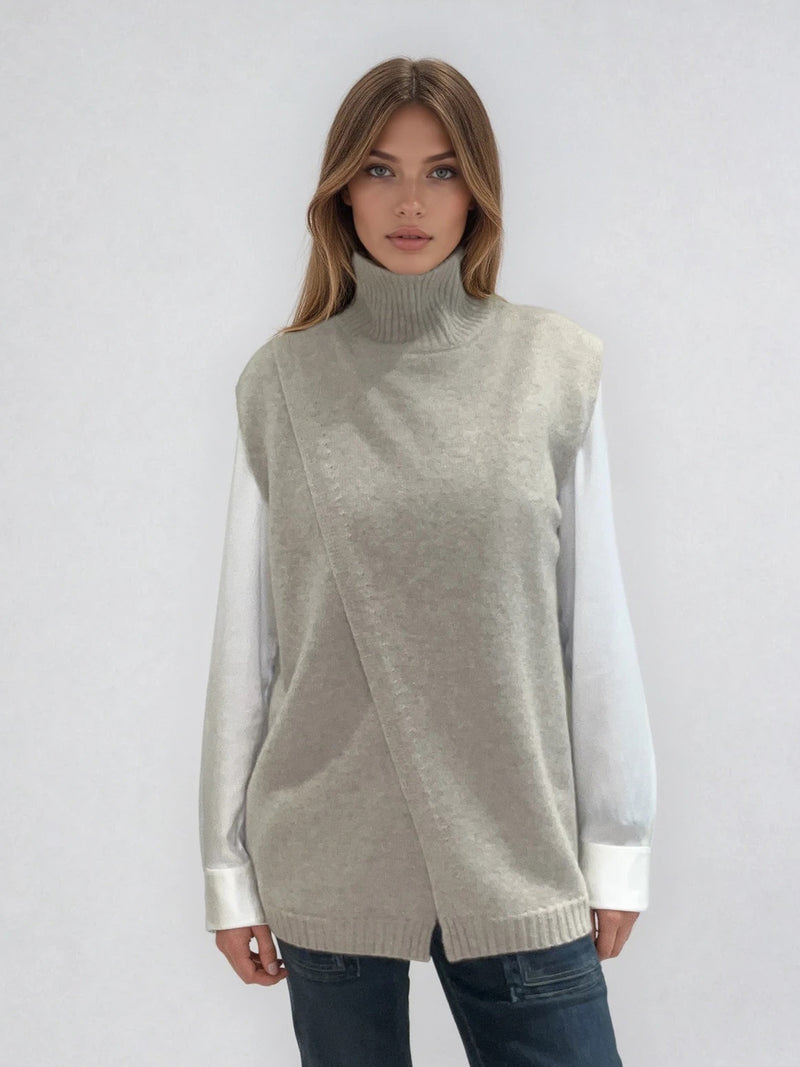 Pull sans manches taupe avec un col montant et une ouverture en diagonale sur le devant formant un croisé. A porter avec un chemisier en dessous. Coupe droite et longue.  42% cachemire, 8% soie, 50% mérinos. Vue face.
