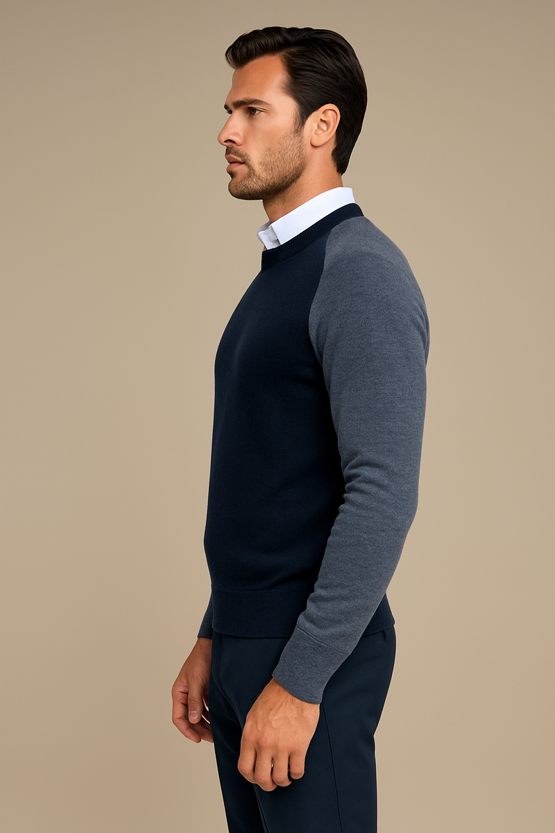 Pull encolure ronde, manches longues pour homme. Le pull est bicolore: gris anthracite sur les manches longues et le dos, le torse et l'encolure sont en marine. Finitions côtes. 42% cachemire, 8% soie et 50% mérinos. Vue profil.