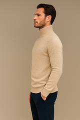 Pull col roulé pour homme beige en 71%cachemire, 19%soie et 10% polyester. Le pull a un col haut très souple, la matière est extrêmement douce et chaude. La forme est droite et les manches longues raglan. Finitions côtes. Vue profil.