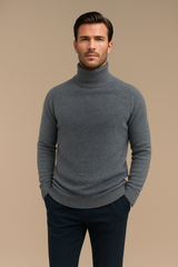 Pull col roulé pour homme gris en 71%cachemire, 19%soie et 10% polyester. Le pull a un col haut très souple, la matière est extrêmement douce et chaude. La forme est droite et les manches longues raglan. Finitions côtes. Vue face.