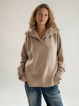 Pull manches longues coloris camel oversize avec un col montant façon camionneur 5 boutons dorés. Le col est souligné par un empiècement plastron et se rabat sur les épaules. Larges côtes. Composition: 42% cachemire, 8% soie, 50% mérinos.