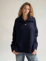 Pull manches longues coloris marine oversize avec un col montant façon camionneur 5 boutons dorés. Le col est souligné par un empiècement plastron et se rabat sur les épaules. Larges côtes. Composition: 42% cachemire, 8% soie, 50% mérinos.