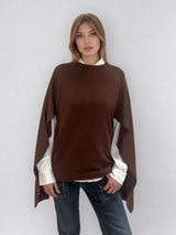 Pull coloris chocolat avec une encolure ronde.  Le modèle est un pull cape: le corps du pull est sans manches, une cape a été associée au niveau des manches raglan devant pour donner un effet chauve-souris . Les bras sont recouverts grâce aux pans de la cape. Vue face.