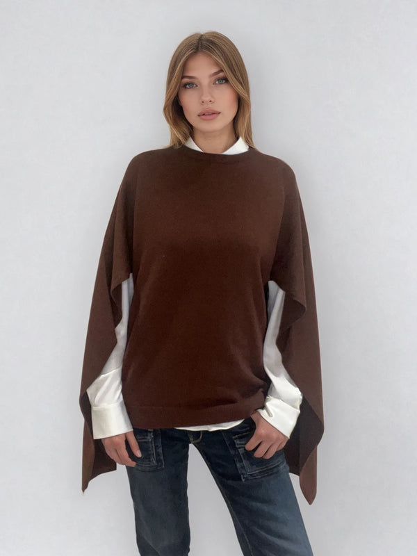 Pull coloris chocolat avec une encolure ronde.  Le modèle est un pull cape: le corps du pull est sans manches, une cape a été associée au niveau des manches raglan devant pour donner un effet chauve-souris . Les bras sont recouverts grâce aux pans de la cape. Vue face.