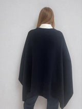 Pull coloris marine avec une encolure ronde.  Le modèle est un pull cape: le corps du pull est sans manches, une cape a été associée au niveau des manches raglan devant pour donner un effet chauve-souris . Les bras sont recouverts grâce aux pans de la cape. Vue dos.
