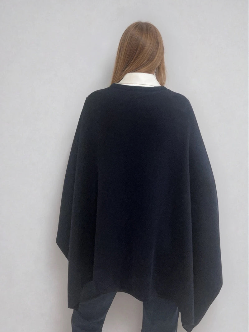 Pull coloris marine avec une encolure ronde.  Le modèle est un pull cape: le corps du pull est sans manches, une cape a été associée au niveau des manches raglan devant pour donner un effet chauve-souris . Les bras sont recouverts grâce aux pans de la cape. Vue dos.