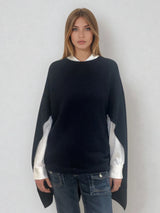 Pull coloris marine avec une encolure ronde.  Le modèle est un pull cape: le corps du pull est sans manches, une cape a été associée au niveau des manches raglan devant pour donner un effet chauve-souris . Les bras sont recouverts grâce aux pans de la cape. Vue face.