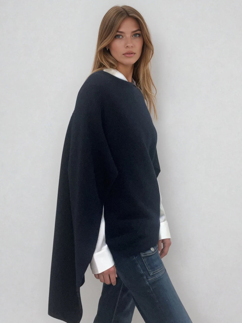 Pull coloris marine avec une encolure ronde.  Le modèle est un pull cape: le corps du pull est sans manches, une cape a été associée au niveau des manches raglan devant pour donner un effet chauve-souris . Les bras sont recouverts grâce aux pans de la cape. Vue profil.