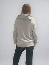 Pull beige en 100%cachemire, manches longues avec une encolure ronde rehaussée d'une capuche. Coupe droite, esprit hoody, se porte assez vague. Les emmanchures sont basses. Un élégant travail de maille formé de 2 bandes termine chaque couture d'assemblage. Finitions côtes. Vue dos.