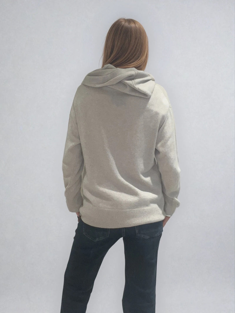 Pull beige en 100%cachemire, manches longues avec une encolure ronde rehaussée d'une capuche. Coupe droite, esprit hoody, se porte assez vague. Les emmanchures sont basses. Un élégant travail de maille formé de 2 bandes termine chaque couture d'assemblage. Finitions côtes. Vue dos.