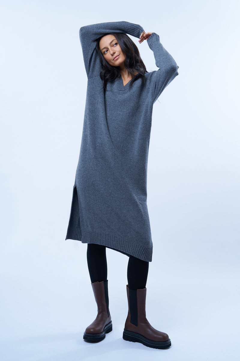 Robe pull manches longues grise avec un col V. Elle est longue et arrive aux mollets. Elle est fendue sur les côtés pour mieux se déplacer. Allure sport chic, confortable et chaude : 42% cachemire, 8% soie, 50% mérinos.