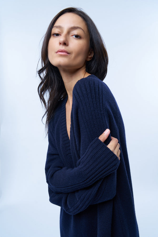 Robe pull manches longues marine avec un col V. Elle est longue et arrive aux mollets. Elle est fendue sur les côtés pour mieux se déplacer. Allure sport chic, confortable et chaude : 42% cachemire, 8% soie, 50% mérinos . Détail Encolure.