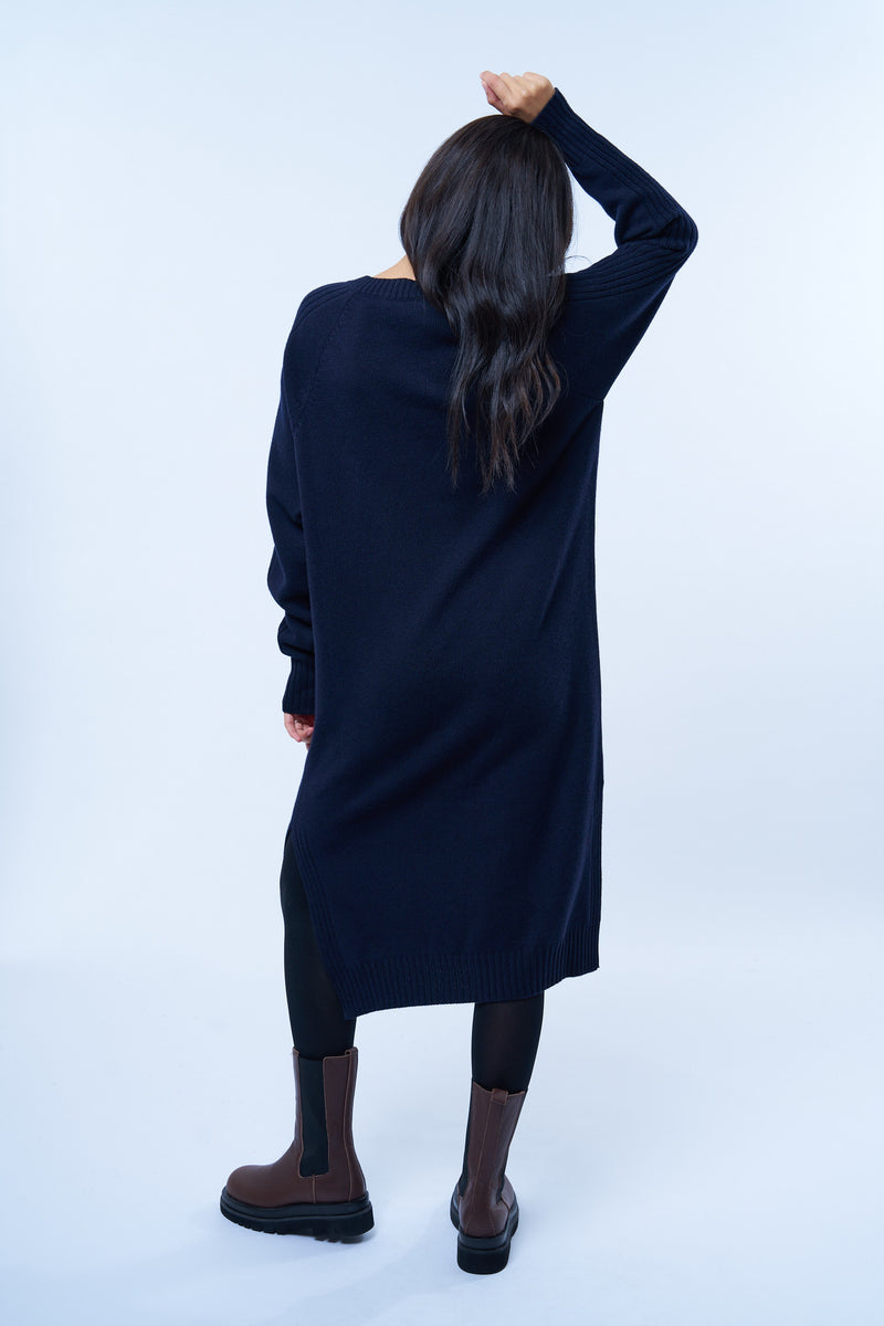 Robe pull manches longues marine avec un col V. Elle est longue et arrive aux mollets. Elle est fendue sur les côtés pour mieux se déplacer. Allure sport chic, confortable et chaude : 42% cachemire, 8% soie, 50% mérinos. Vue dos.