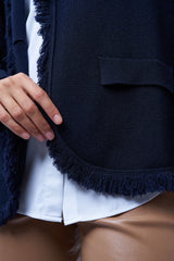 Veste manches longues marine en cachemire, laine et mérinos. La veste est bordée tout le long du col tailleur et en bas de petites franges marines en laine, se ferme avec 1 bouton et a  2 fausses poches sur les côtés. Coupe droite. Vue détail franges sur le pourtour de bas de la veste.
