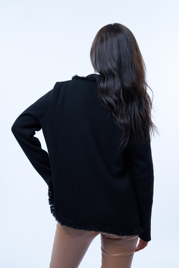 Veste manches longues noire en cachemire, laine et mérinos. La veste est bordée tout le long du col tailleur et en bas de petites franges noires en laine, se ferme avec 1 bouton et a  2 fausses poches sur les côtés. Coupe droite. Vue dos.