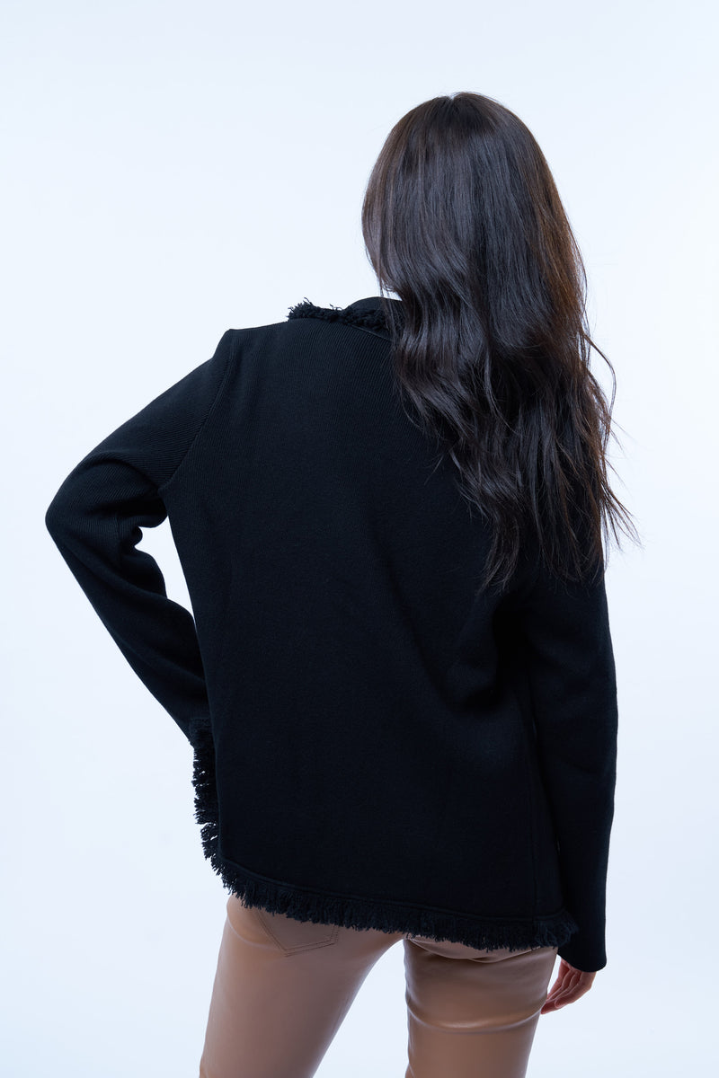 Veste manches longues noire en cachemire, laine et mérinos. La veste est bordée tout le long du col tailleur et en bas de petites franges noires en laine, se ferme avec 1 bouton et a  2 fausses poches sur les côtés. Coupe droite. Vue dos.
