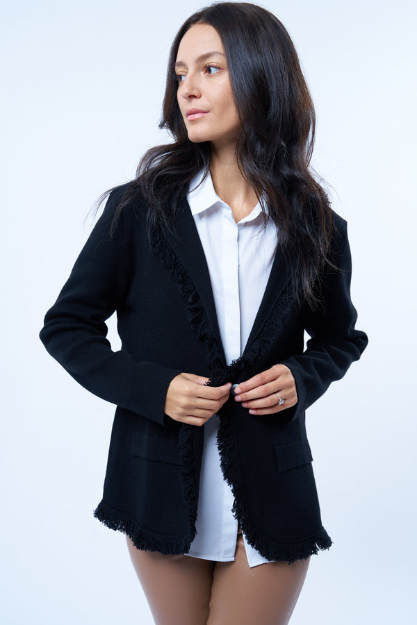 Veste manches longues noire en cachemire, laine et mérinos. La veste est bordée tout le long du col tailleur et en bas de petites franges noires en laine, se ferme avec 1 bouton et a  2 fausses poches sur les côtés. Coupe droite.