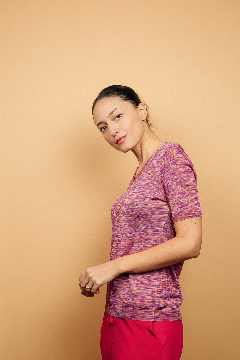 T-shirt femme avec un imprimé rose : mélange de nuances de rose, de violet, de blanc, dans un graphisme strié, forme droite, col V, manches courtes en maille viscose légèrement brillante, ressenti fluide à associer avec un pantalon en viscose  uni rose fushia, vue côté.