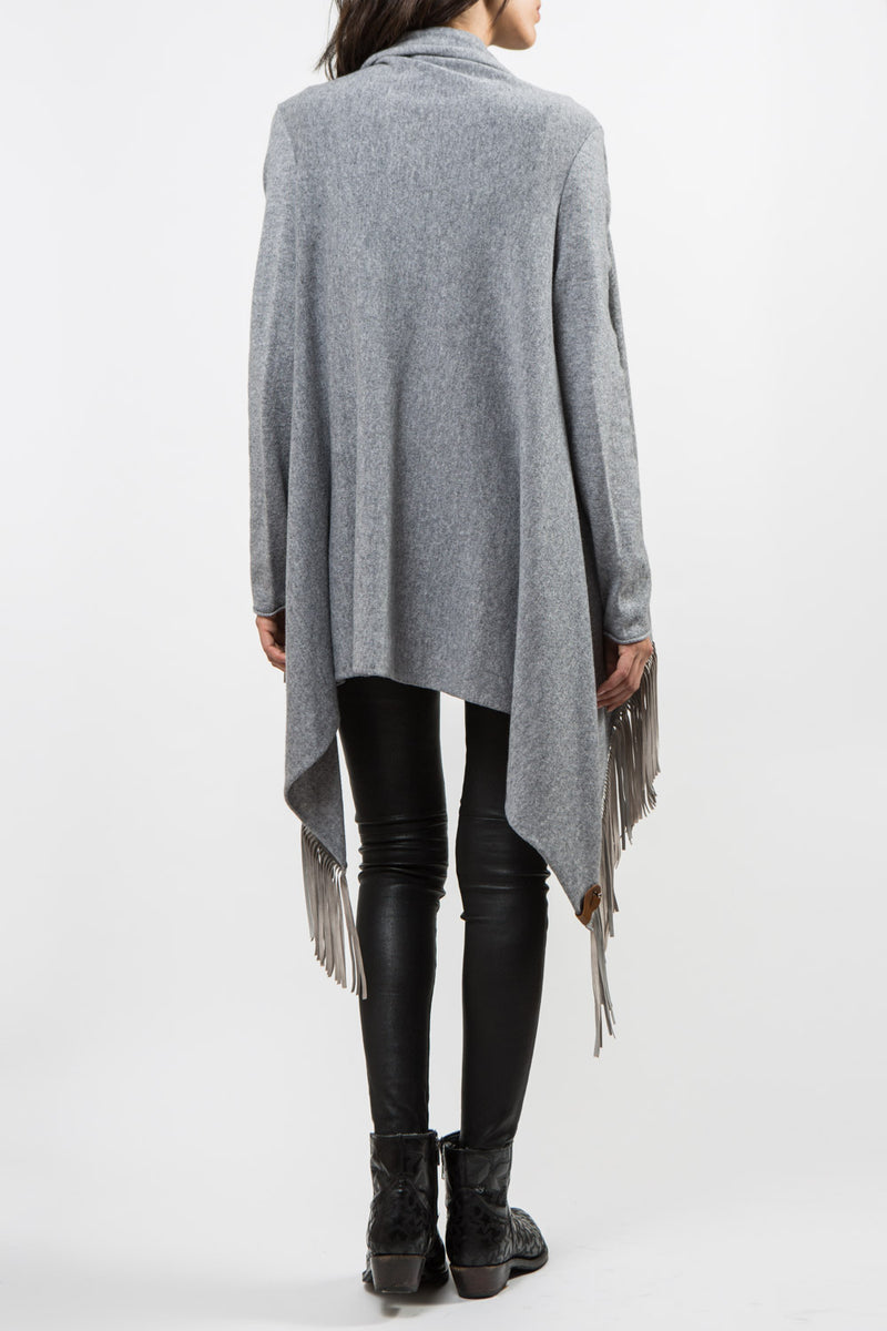 Gilet APACHE coloris gris clair 100% cachemire manches longues avec des franges coloris de la même couleur en cuir d'agneau plongé de 15 cm sur les 2 côtés, il n'y a pas de fermeture. Les franges bougent avec le gilet. Le col se positionne comme un drapé. Vue dos.